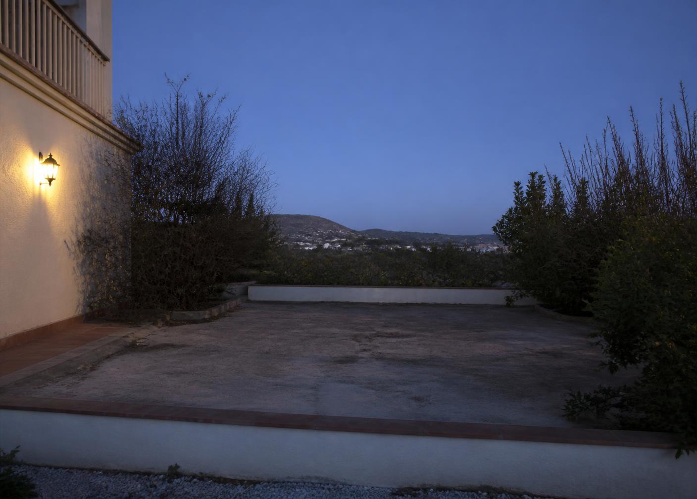 Terraza de una vivienda al anochecer, sin piscina, antes de la obra
