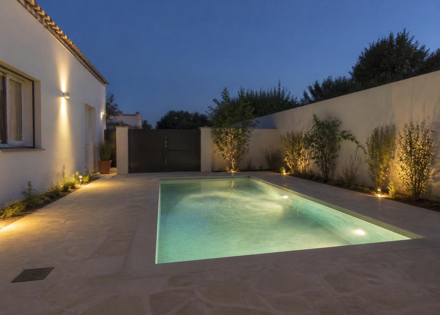 Piscina terminada al anochecer con iluminación integrada suave y vegetación alrededor